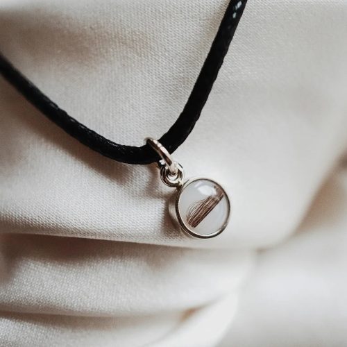 Surround - A circular gold pendant with breast milk or baby hair